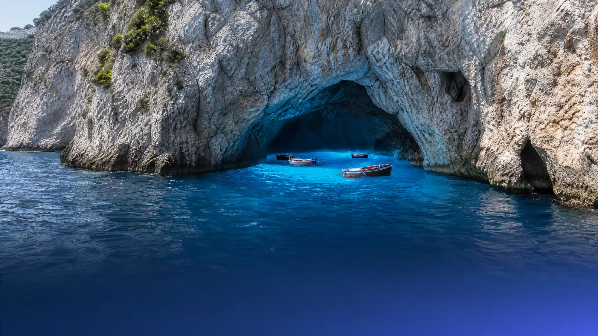 The Blue Grotto is a natural sea cave on the coast of Capri. Visitors enter by lying flat in small wooden rowboats to see the glowing azure water.