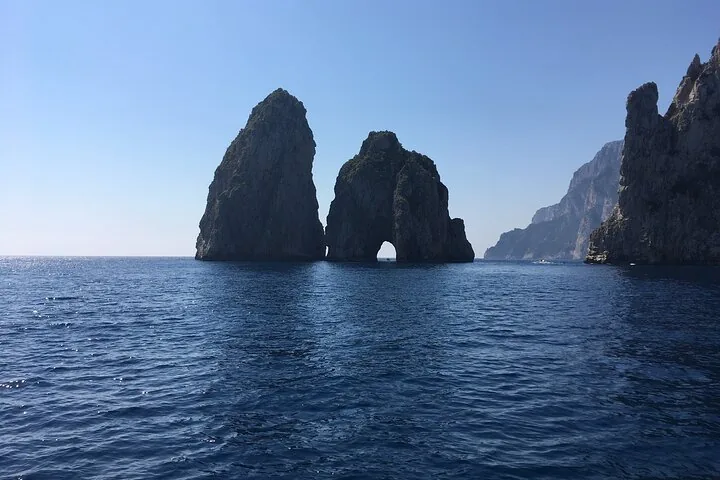 View of the majestic Faraglioni rock formations emerging from the blue sea.