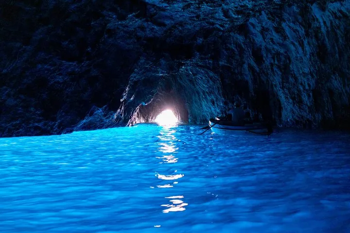 A rowboat floating on the radiant blue water inside the Blue Grotto.