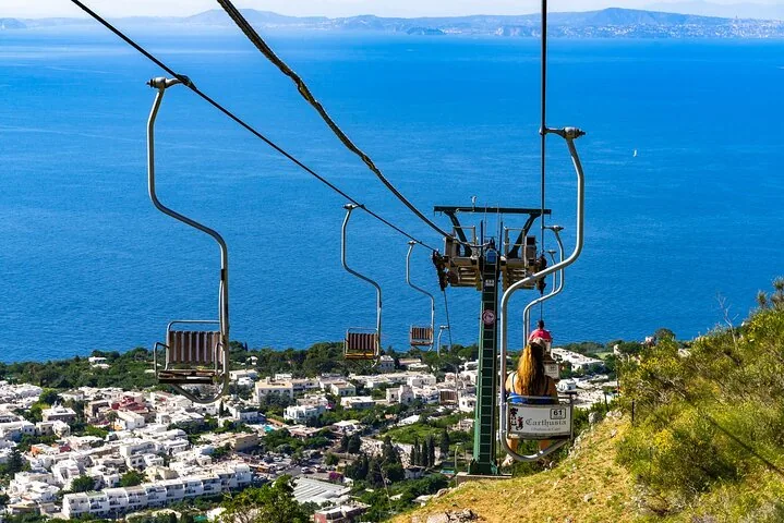 Riding a chairlift with a spectacular view of the town and sea below.